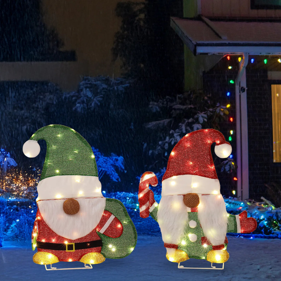 Two lit Christmas gnome figures in garden