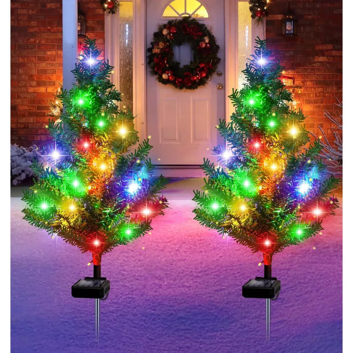 Four solar mini Christmas trees lit on lawn